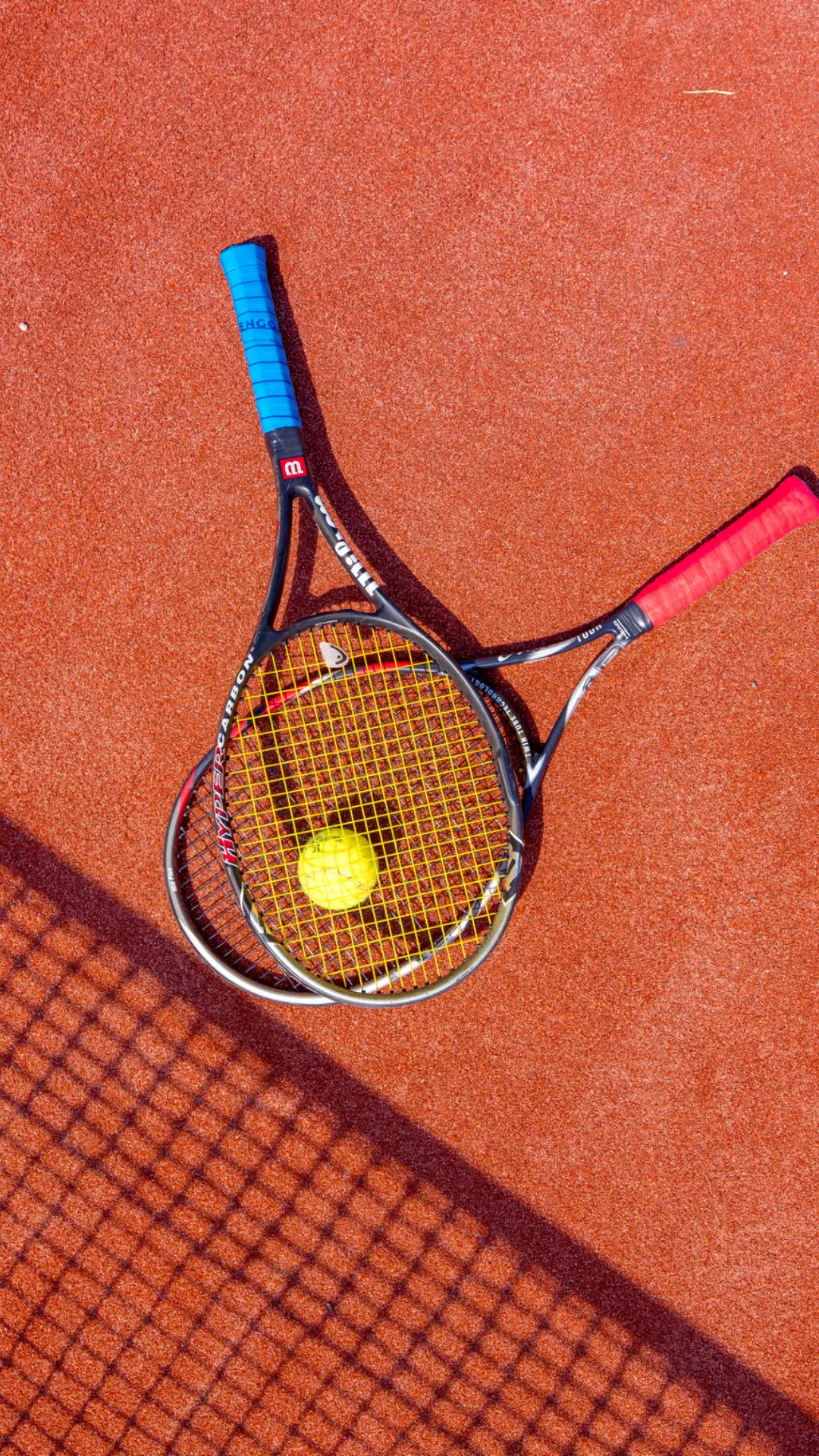 Tennis racket and ball on the red court surface