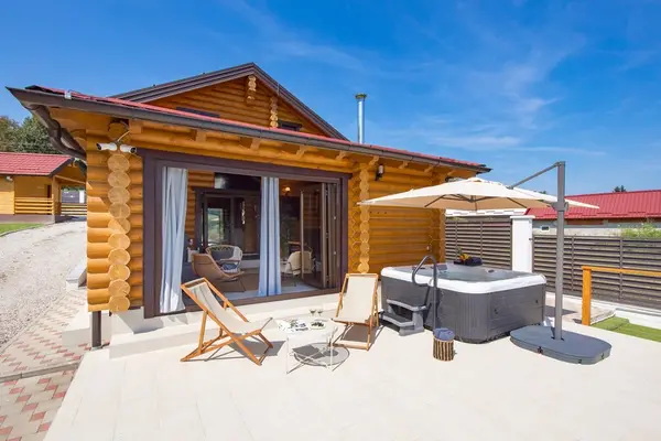 Jacuzzi i ležaljke na terasi uz drvenu kuću
