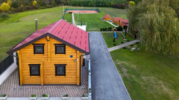 Drvena kuća iz zraka, u pozadini dječje igralište i teniski teren