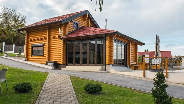 Drvena kuća i ostakljena terasa gledano iz vrta
