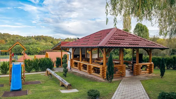 Drvena sjenica s crvenim krovom i dječje igralište