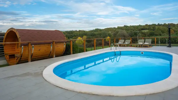 Ovalni bazen, bačvasta sauna i ležaljke na terasi