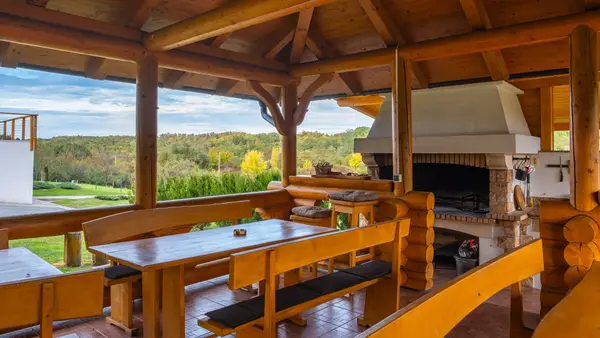 Sjenica iznutra: dugi stolovi s klupama i zidani roštilj