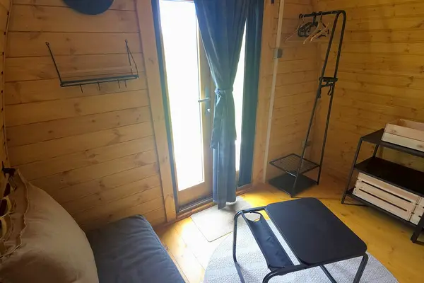 Cabin entrance from inside: glazed door, clothes rack and small table