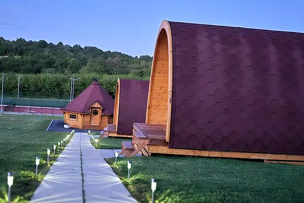 Glamping cabins and the barbecue hut at dusk, tennis court behind